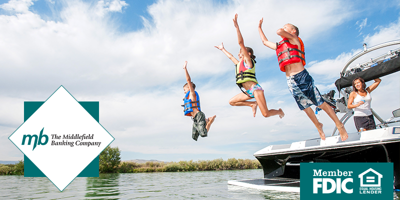 People wearing life vests jumping off of a small boat