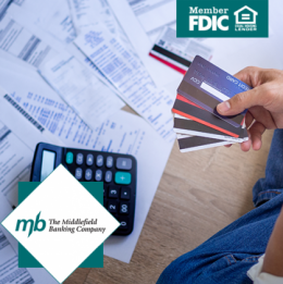 Man holding stack of credit cards in his hands with a calculator on the floor and various financial reports spread about the floor