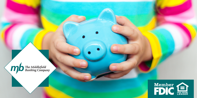 a child's hands holding a blue piggy bank 